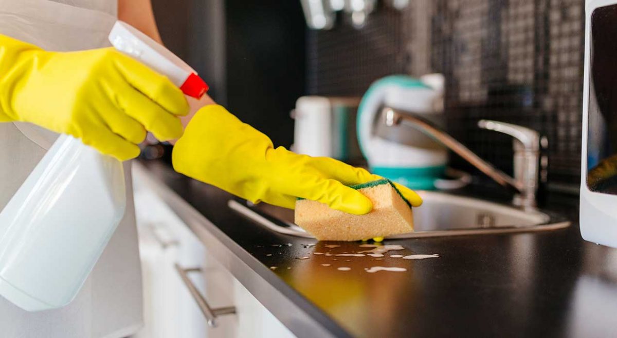 A woman wiping down a sink during house cleaning